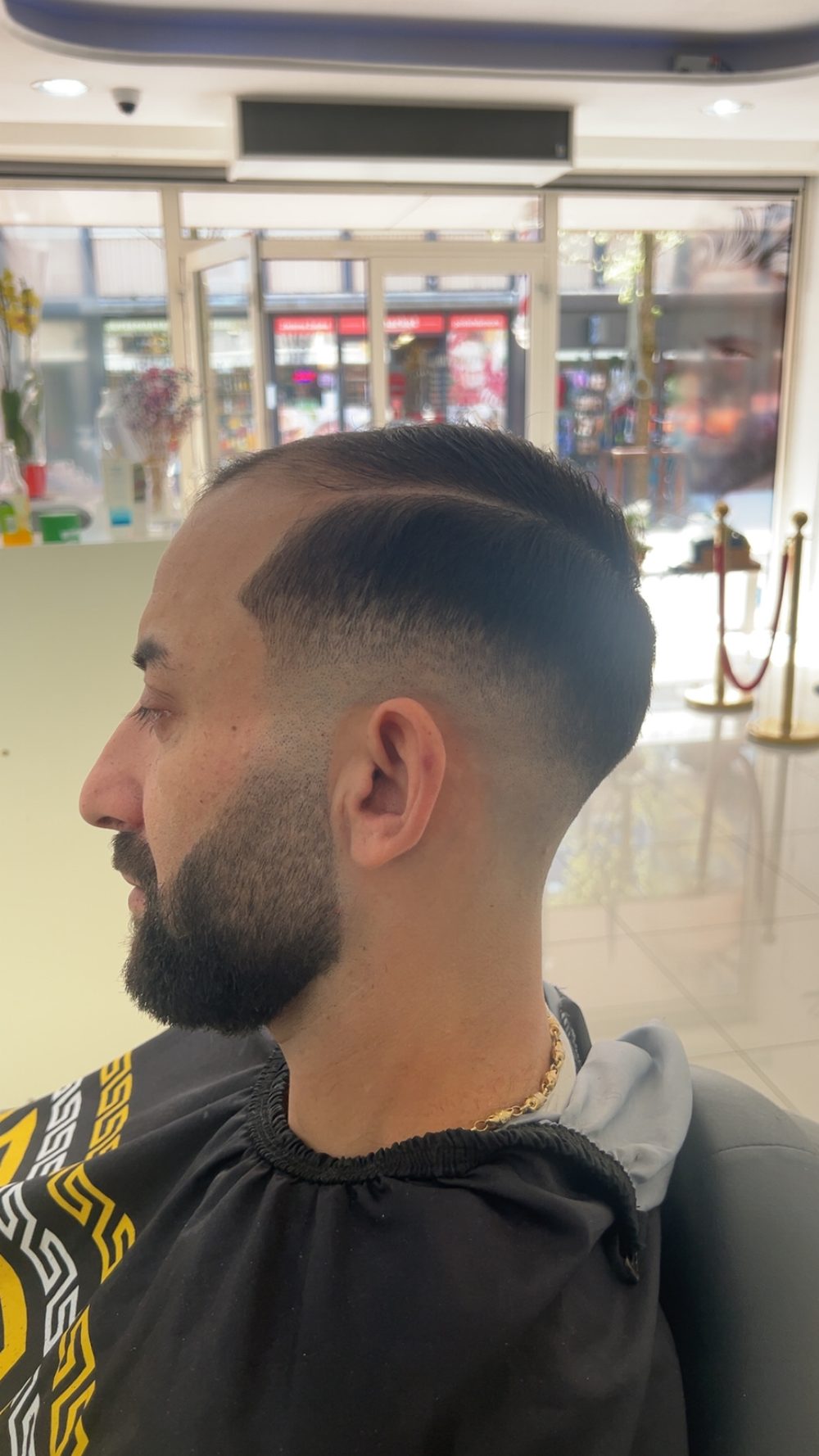 Zijaanzicht van een klant met een fade, een strakke scheiding en een verzorgde baard